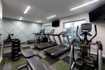 a gym with various cardio equipment and a window at 310 at Nulu Apartments-Student, Kentucky, 40202